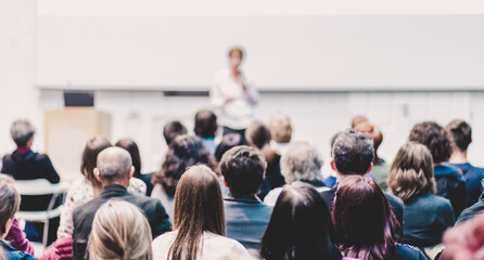 business and entrepreneurship symposium. female speaker giving a talk at business meeting. audience 