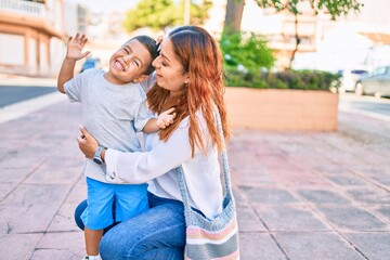 Adorable latin mother and son smiling happy hugging at the city.