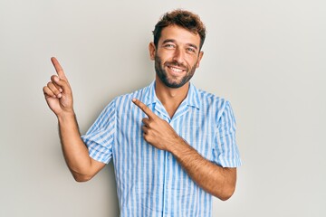 Poster - Handsome man with beard wearing casual shirt smiling and looking at the camera pointing with two hands and fingers to the side.