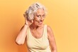© Krakenimages.com - Senior grey-haired woman wearing casual clothes smiling with hand over ear listening an hearing to rumor or gossip. deafness concept.