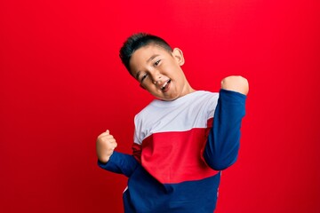 Wall Mural - Little boy hispanic kid wearing casual winter sweater celebrating surprised and amazed for success with arms raised and eyes closed