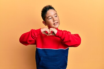 Sticker - Little boy hispanic kid wearing casual sweatshirt smiling in love showing heart symbol and shape with hands. romantic concept.