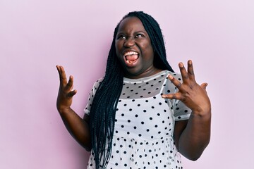 Sticker - Young black woman with braids wearing casual clothes crazy and mad shouting and yelling with aggressive expression and arms raised. frustration concept.