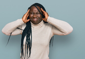 Wall Mural - Young black woman with braids wearing casual winter sweater suffering from headache desperate and stressed because pain and migraine. hands on head.