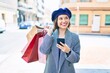 © Krakenimages.com - Young beautiful girl with french style holding shopping bags using smartphone at street of city