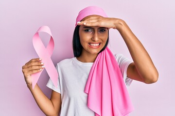 Poster - Young brunette woman wearing head scarf and holding pink cancer ribbon stressed and frustrated with hand on head, surprised and angry face