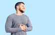 © Krakenimages.com - Young handsome man wearing casual sweater with hand on stomach because nausea, painful disease feeling unwell. ache concept.