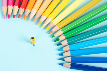 Poster - Selective focus shot of a figurine surrounded with colorful pencils