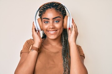 Poster - Young african american woman with braids listening to music using headphones smiling with a happy and cool smile on face. showing teeth.