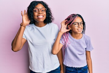 Sticker - Beautiful african american mother and daughter wearing casual clothes and glasses smiling with hand over ear listening an hearing to rumor or gossip. deafness concept.