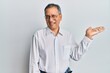 © Krakenimages.com - Middle age indian man wearing casual clothes and glasses smiling cheerful presenting and pointing with palm of hand looking at the camera.
