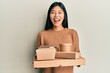 Young chinese woman holding take away food smiling and laughing hard out loud because funny crazy joke.