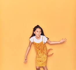 Sticker - Adorable hispanic child girl wearing casual dress and diadem smiling happy. Jumping with smile on face over isolated yellow background