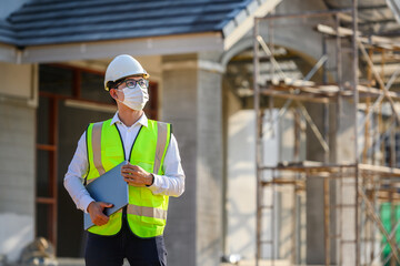 Foreman or young handsome Asian engineer Wear a helmet and a mask Control construction on the construction site