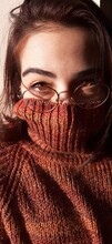 Close-up Portrait Of Woman Wearing Eyeglasses Covering Face With Sweater