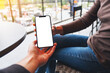 © Farknot Architect - Mockup image of a woman holding and showing white mobile phone with blank black desktop screen to her friend