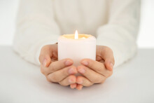 Closeup Shot Of Hands Holding An Illuminated White Candle