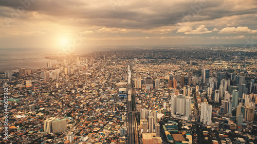 Plakat Sun cityscape of port town Manila aerial. Sunrise light over modern buildings, skyscrapers of downtown streets. Metropolis city of Manila, Philippines, Asia. Cinematic summer soft drone shot