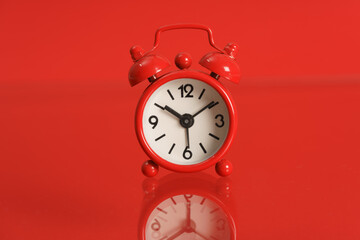 Small alarm clock on red background