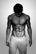 © Dragosh - Front portrait of a handsome brunette man with muscular body posing at studio, looking down. Black and white photo.