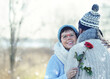 lachende Frau mit roter Rose umarmt ihren Mann