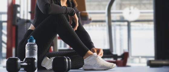 Sporty female take a rest sitting in fitness gym after exercise, Banner with copy space