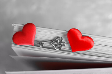 two red hearts and a key on the pages of a book, monochrome retro effect, couple relationship  falling in love and love concept