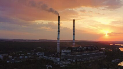 Wall Mural - Harmful factory in the countryside. Industry with tower pipes on the evening sky with setting sun. Chemical smoke from manufacture pollutes the air. View from above.