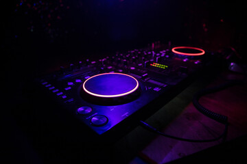 Wall Mural - DJ console deejay-mixing desk in dark with colorful light. Mixer equipment entertainment DJ station.