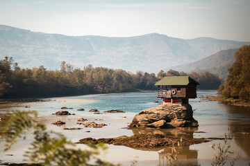 Sticker - Beautiful shot of a house on a rock surrounded by river Drina and greenery covered hills in Serbia