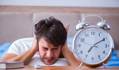 Wall Mural - Man in bed frustrated suffering from insomnia with an alarm cloc