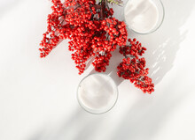 Two White Candles With A Red Flower And Berries