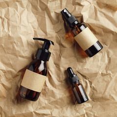 Wall Mural - set of amber glass cosmetic bottles on kraft paper top view. flat lay dropper, dispenser, spray bott