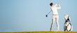 Asian man golfer standing  on slope  with golf bag hitting  golf ball on blue sky background  at golf course