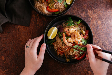 Wall Mural - Stir fried noodles with shrimps and vegetables in a wok on dark