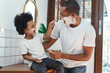 African American father and little son spend time together have a fun laughing while shaving foam on their faces in the bathroom. Morning routine in bathroom concept.
