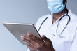 © Wavebreak Media - Mixed race female doctor wearing face mask standing and using digital tablet