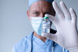 © Wavebreak Media - Caucasian male doctor wearing face mask standing and showing coronavirus vaccine