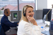 © Wavebreak Media - Caucasian businesswoman sitting wearing headphones looking at camera and smiling in modern office