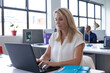 © Wavebreak Media - Caucasian businesswoman sitting using a laptop in a modern office