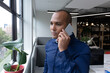 © Wavebreak Media - Mixed race businessman standing by window using smartphone in a modern office