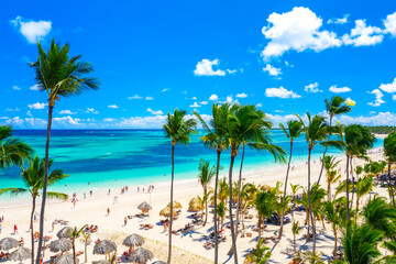 Aerial drone view of beautiful atlantic tropical beach with palms, straw umbrellas and boats. Bavaro, Punta Cana, Dominican Republic. Vacation background.