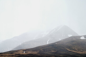 Sticker - Grassy mountain ridge with snow against foggy sky