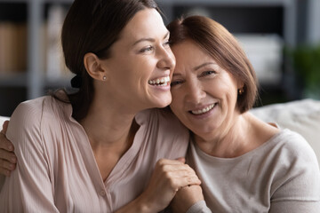 close up head shot portrait smiling mature mother and grownup daughter cuddling, family enjoying ten