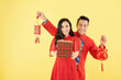 © DragonImages - Smiling woman with Lunar New Year gift and her boyfriend showing wall decorations with best wishes inscription