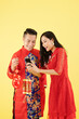 © DragonImages - Excited positive young Asian woman showing photo on smartphone screen to boyfriend when they are holding decorations with best wishes inscription