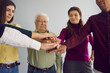 © Studio Romantic - Cropped image of a group of co-workers of different ages and nationalities folds their arms as a symbol of cooperation. Concept of unity and teamwork. Selective focus.