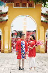 Sticker - cheerful young asian couple with blooming peach branches visiting temple to celebrate lunar new year