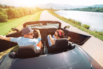 Wall Mural - Couple in love getting into the convertible auto cabriolet and starting a trip. Couple honeymoon, traveling or vacation concept image.