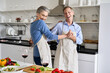 © insta_photos - Happy affectionate older middle aged couple laughing, dancing, preparing healthy meal in modern kitchen apartment. Senior husband and wife enjoying dance having fun celebrating Valentines day at home.